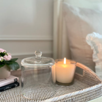 Clear glass cloche dome styled over a candle on a tray for elegant home display.