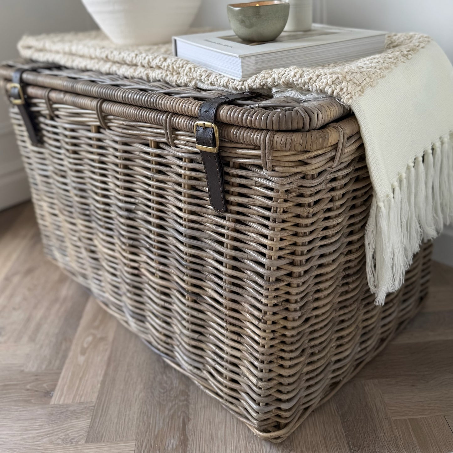 Wicker storage trunk with a blanket on a wooden floor