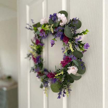 Faux lavender wreath with purple and white blooms, eucalyptus and peach wildflowers, 40 cm diameter styled on a white door.