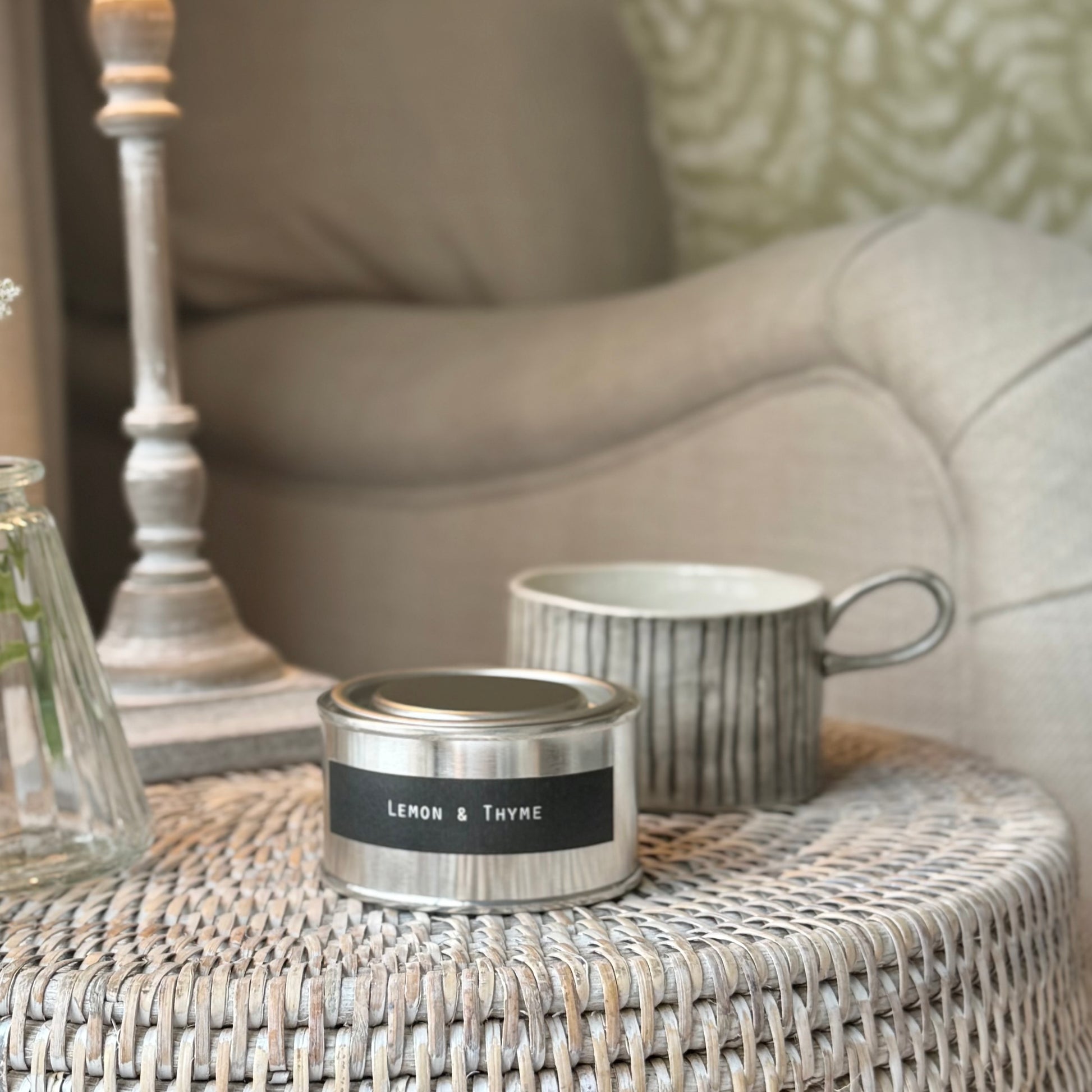 Candle and mug candle holder on a rattan table and lamp.