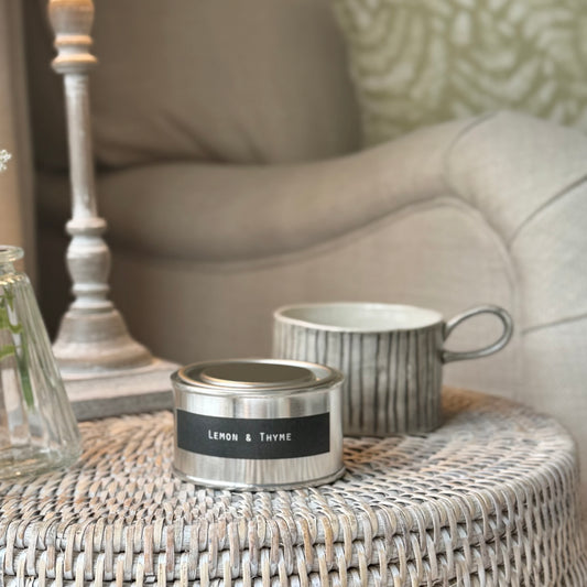 Candle and mug candle holder on a rattan table and lamp.