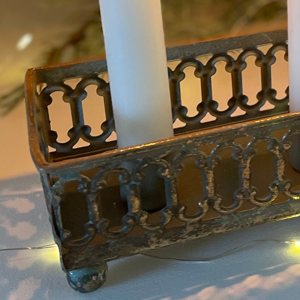 Close up of softly distressed tin candle holder with candles lit.