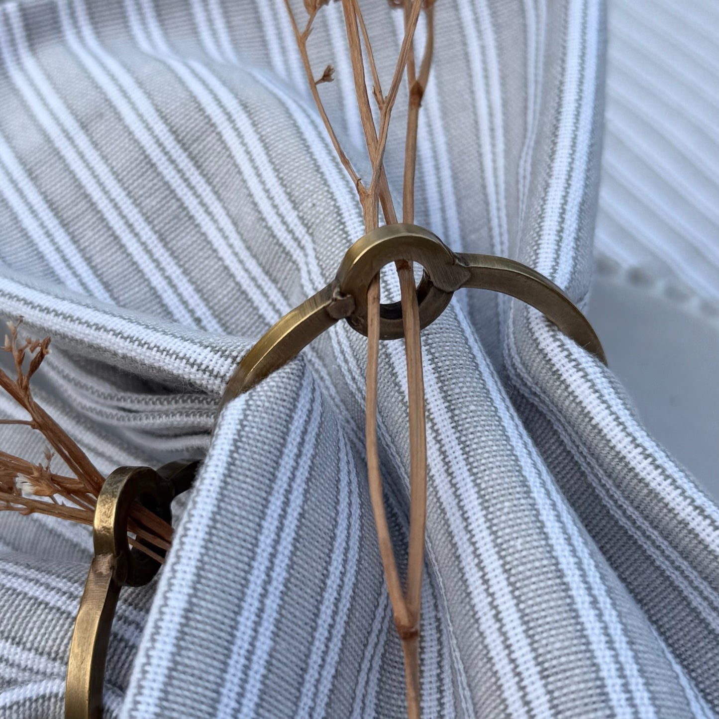 Elegant metal napkin rings styled on a table setting, perfect for adding timeless charm and seasonal touches like sprigs of rosemary or gypsophila.