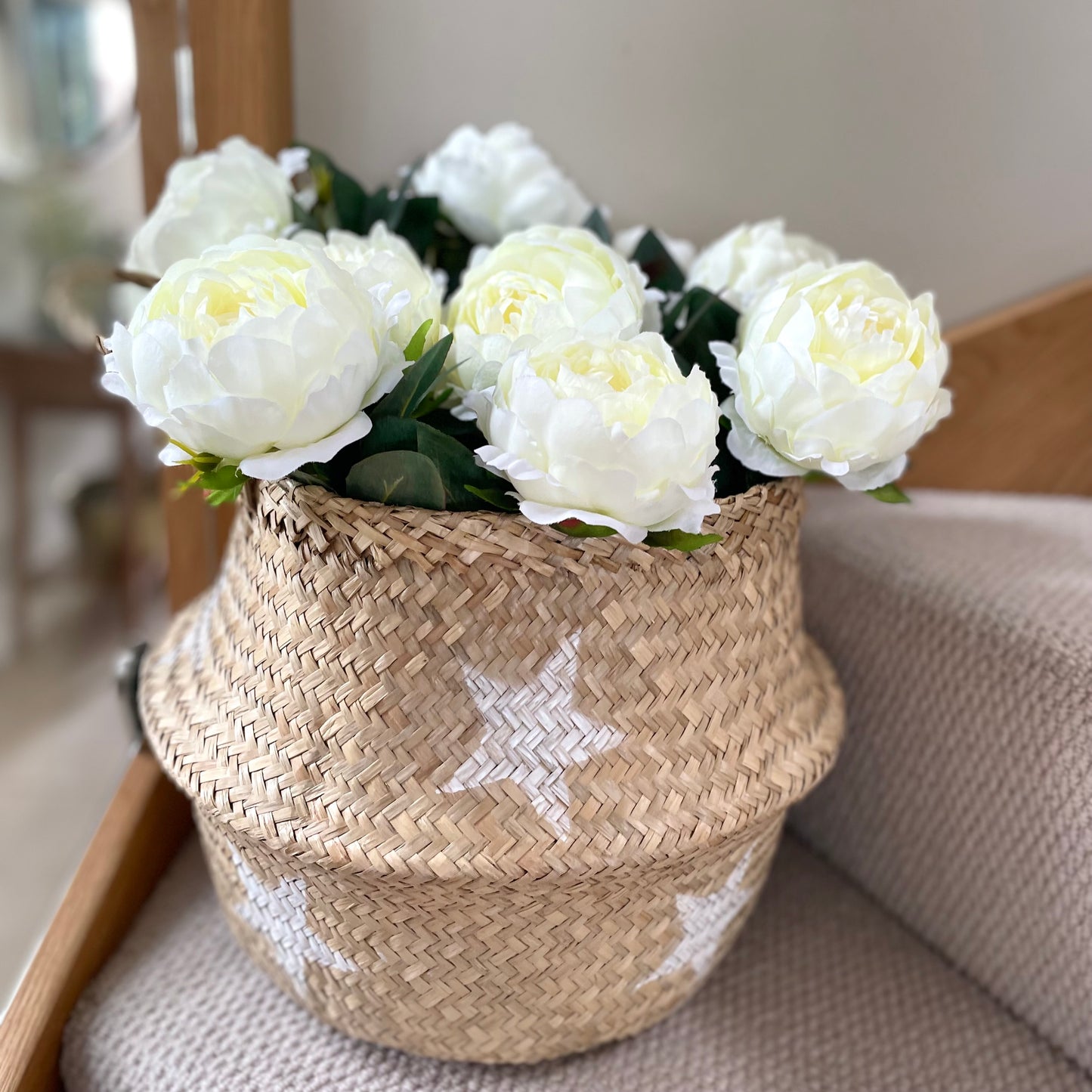 Millie cream peony stem with delicate lifelike blooms and green leaves, styled in a decorative basket.