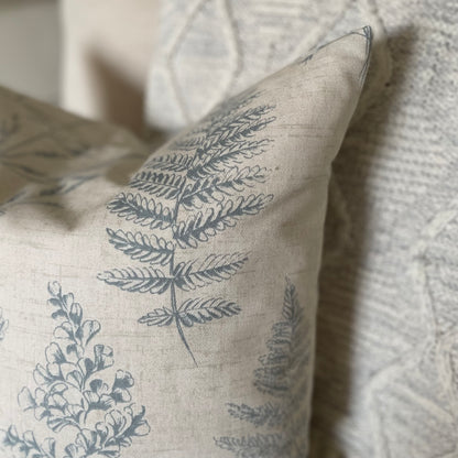 Natural cushion with blue leaf pattern styled on a neutral armchair with a throw.
