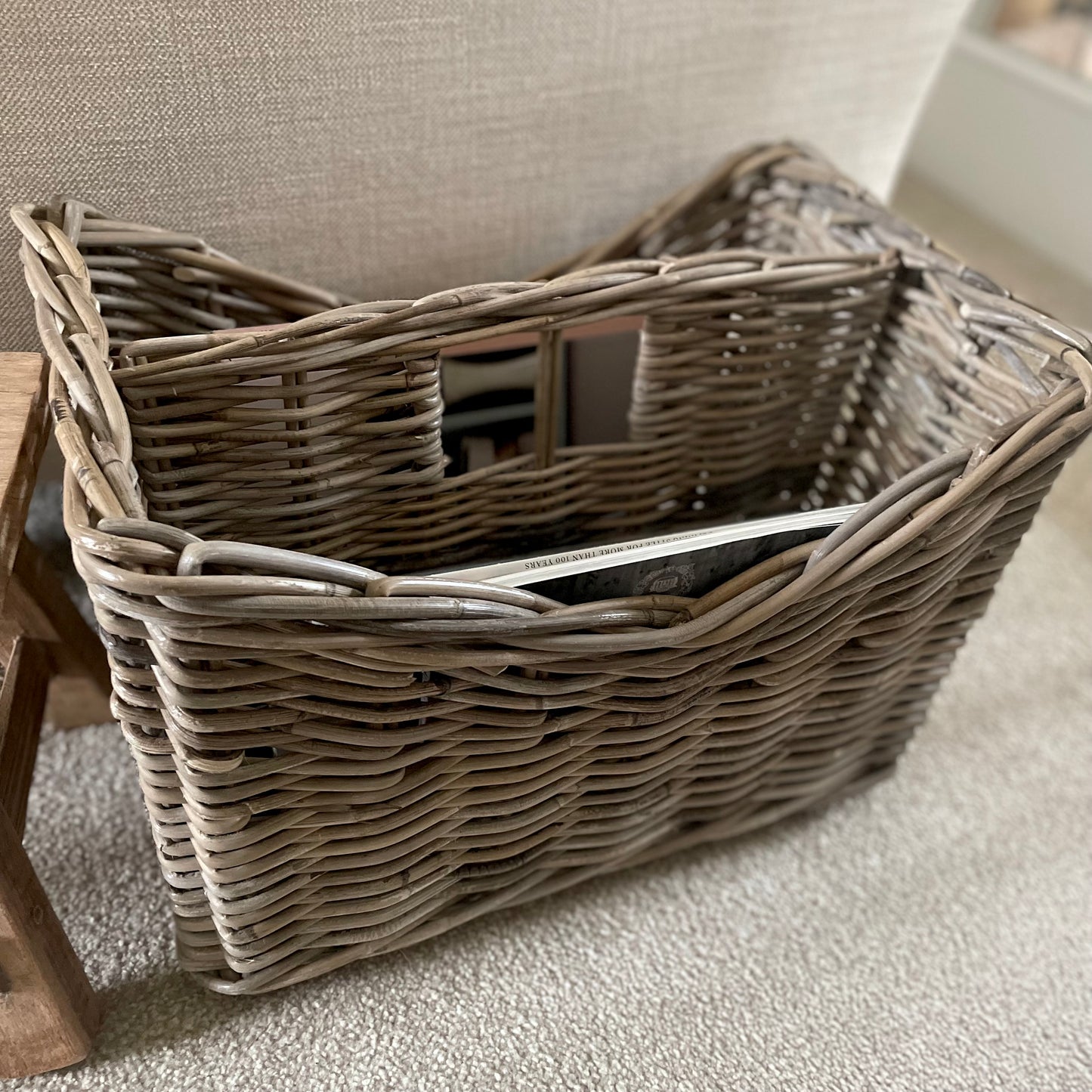 Natural rattan storage basket with integral handle. Styled in a cosy living room.