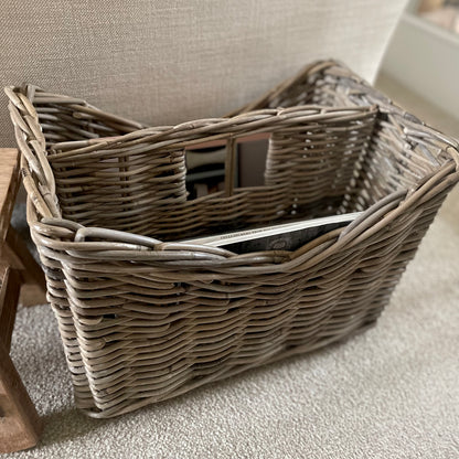 Natural rattan storage basket with integral handle. Styled in a cosy living room.
