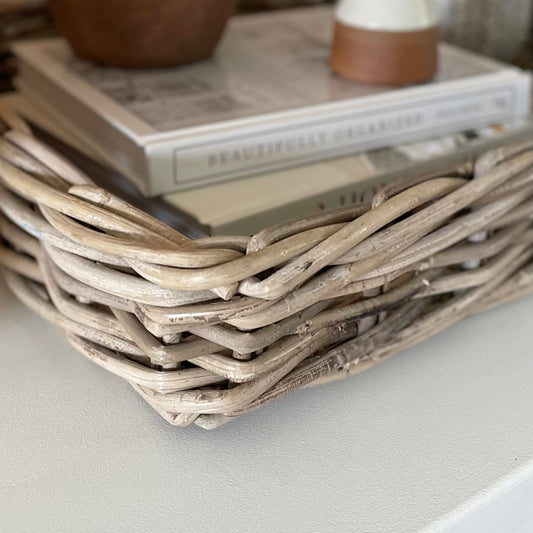Handwoven natural rattan tray holding decorative items, adding warmth and texture to a neutral interior.