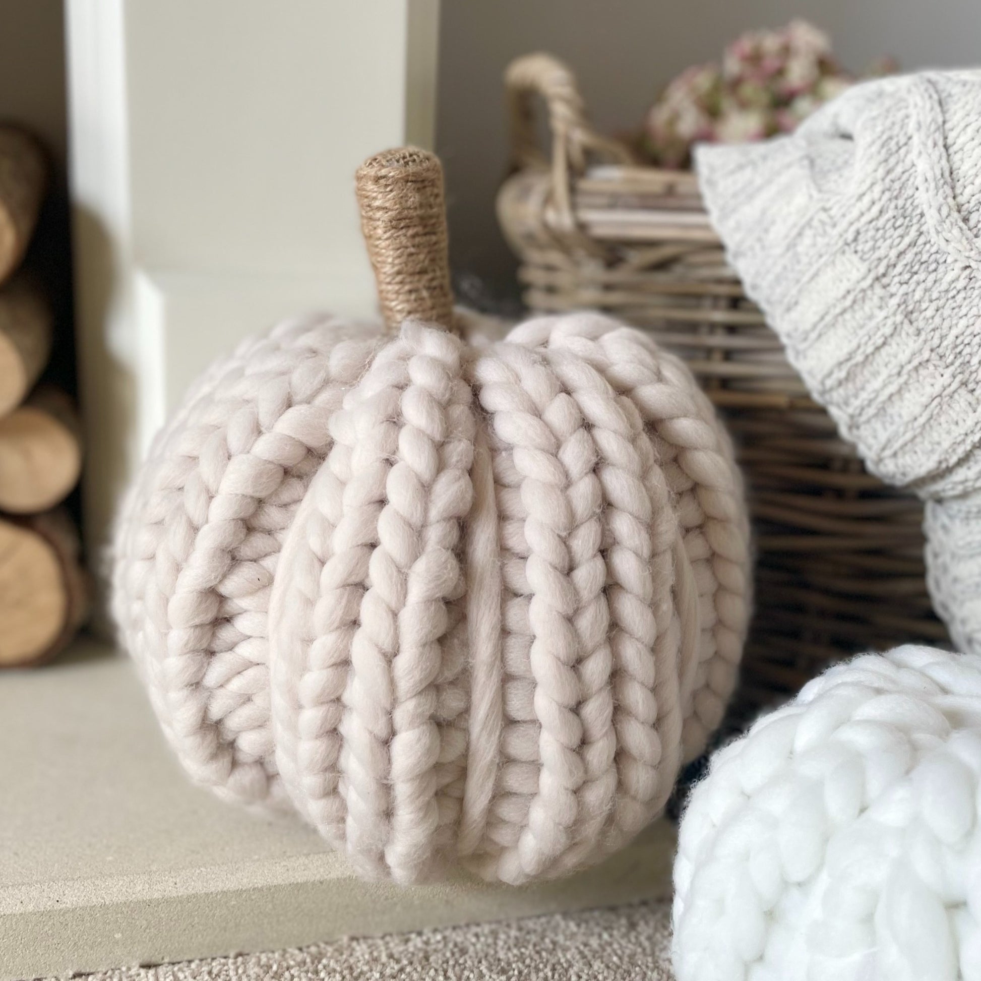 Oatmeal chunky knitted pumpkin with twine wrapped stalk styled on a living room fireplace.