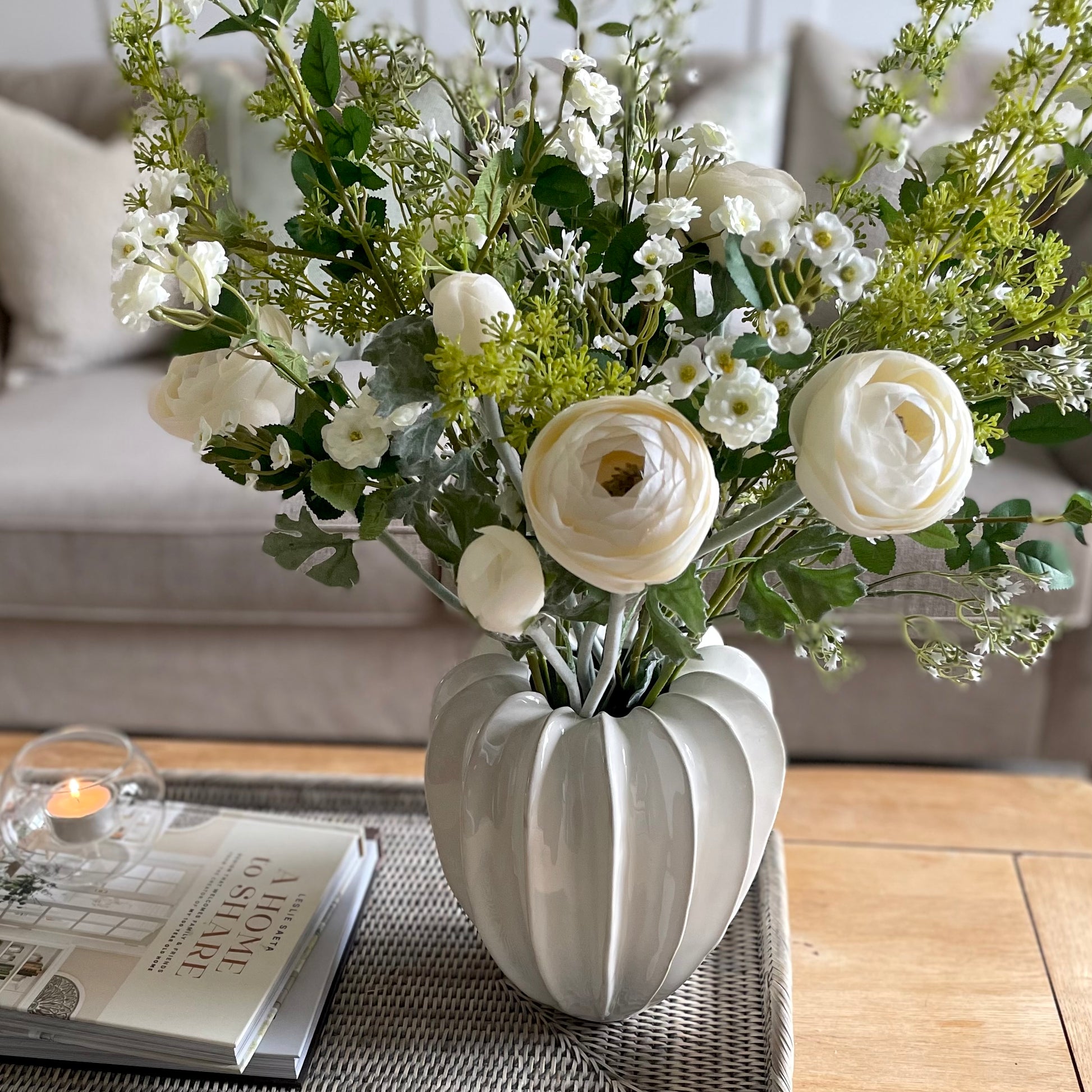 Unique shaped Olivia vase styled with white bouquet arrangement. Styled on a coffee table in a cosy living room.