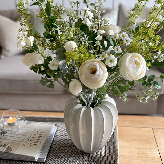 Unique shaped Olivia vase styled with white bouquet arrangement. Styled on a coffee table in a cosy living room.