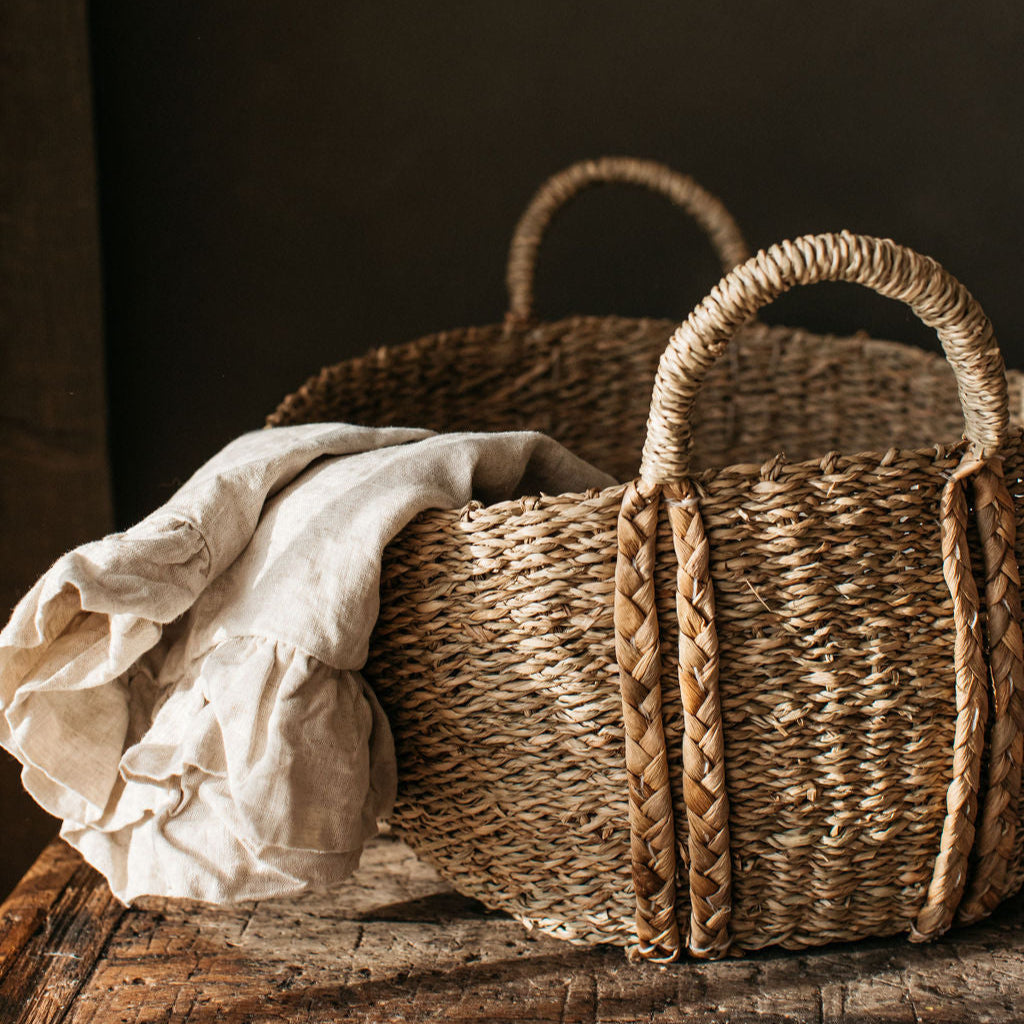 Deep oval handwoven seagrass basket with plaited handles, perfect for storing blankets, toys, or everyday essentials with rustic charm.