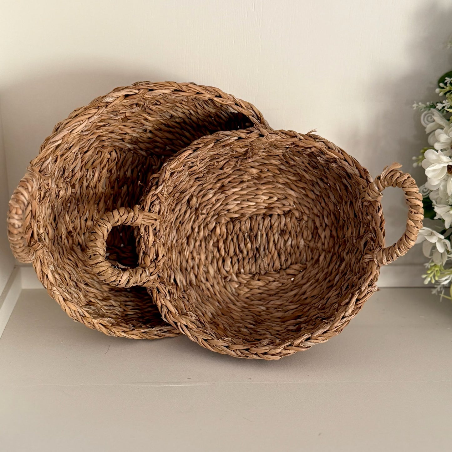 Two woven baskets with handles on a light surface.