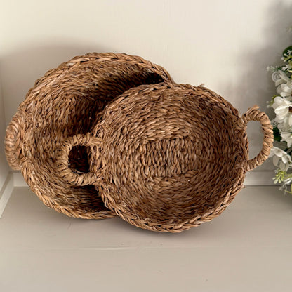 Two woven baskets with handles on a light surface.