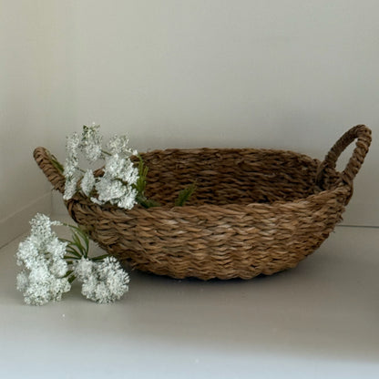 Woven basket with white flowers on a light surface and background