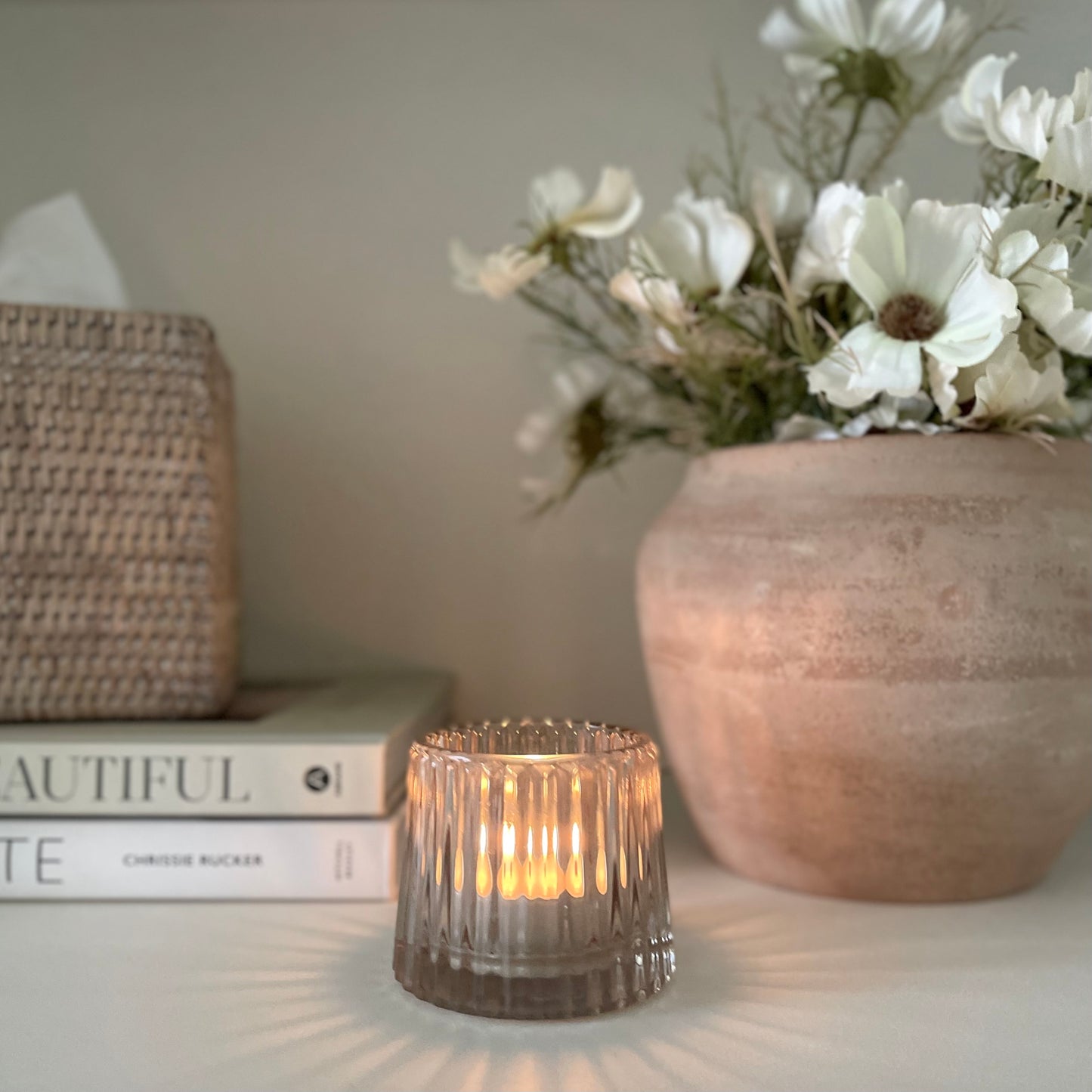 Elegant glass light pink candle holder styled in a cosy room with plants and a book.