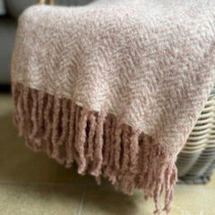 Textured blanket with fringe, draped on a basket.