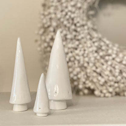 Porcelain Christmas trees grouped on shelf for seasonal decor. Styled with white wreath.