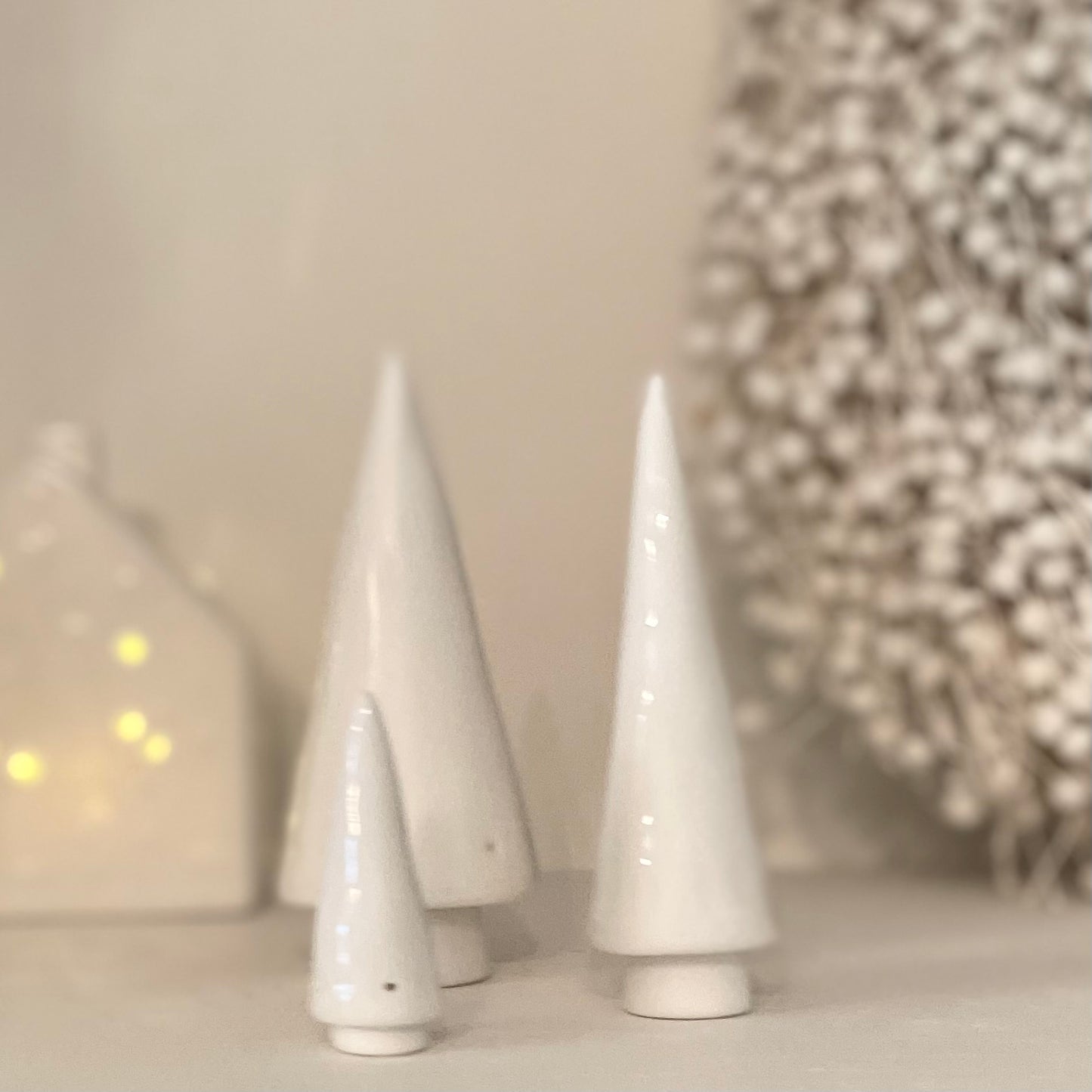 Minimalist porcelain tree set for festive home styling. Displayed on a shelf with a white wreath and LED porcelain house.
