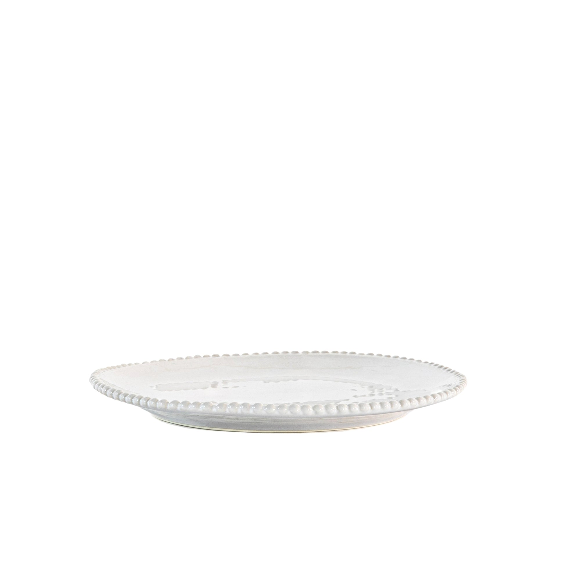 White porcelain side plate with organic shape and beaded detailing around the rim. Styled in front of white background.