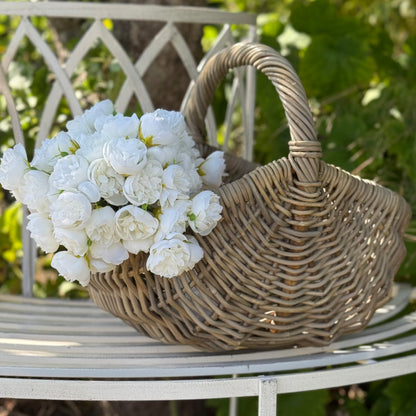 Handwoven rattan basket with circular handle, perfect for flowers, kindling or home storage.