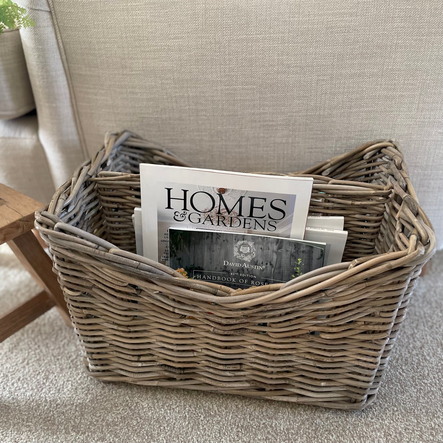 Handmade rattan magazine storage basket with two compartments. Styled in a cosy neutral living room.