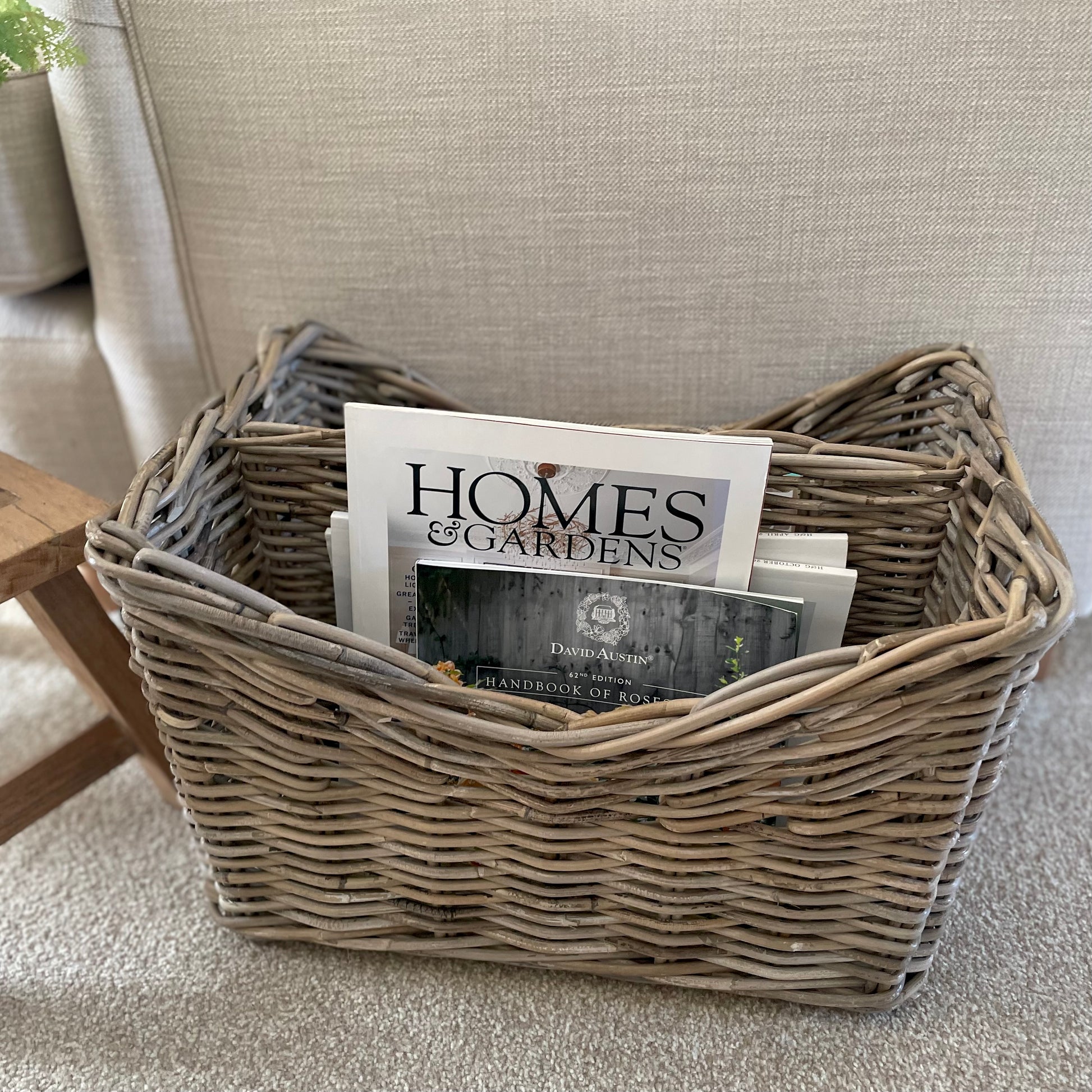 Handmade rattan magazine storage basket with two compartments. Styled in a cosy neutral living room.