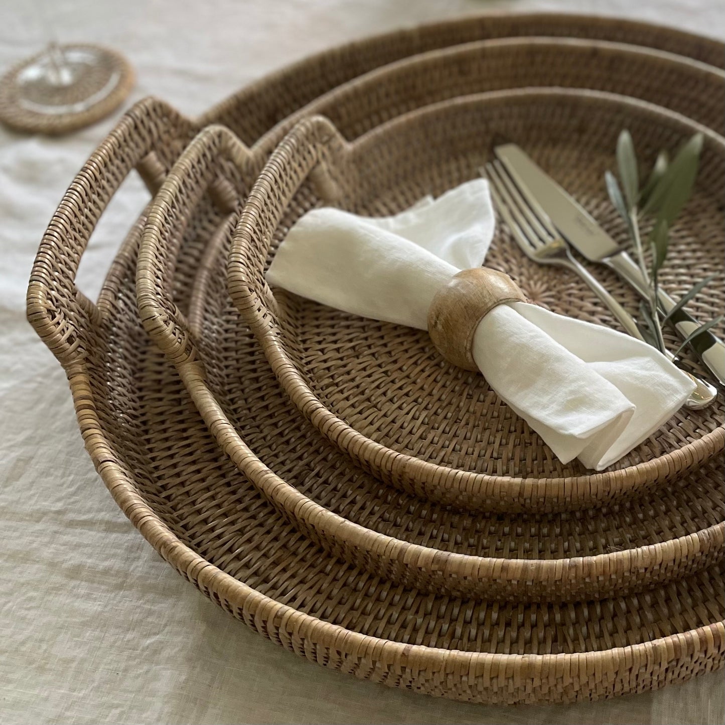Whitewashed rattan tray with carry handles styled on a dining table holding napkin and cutlery.