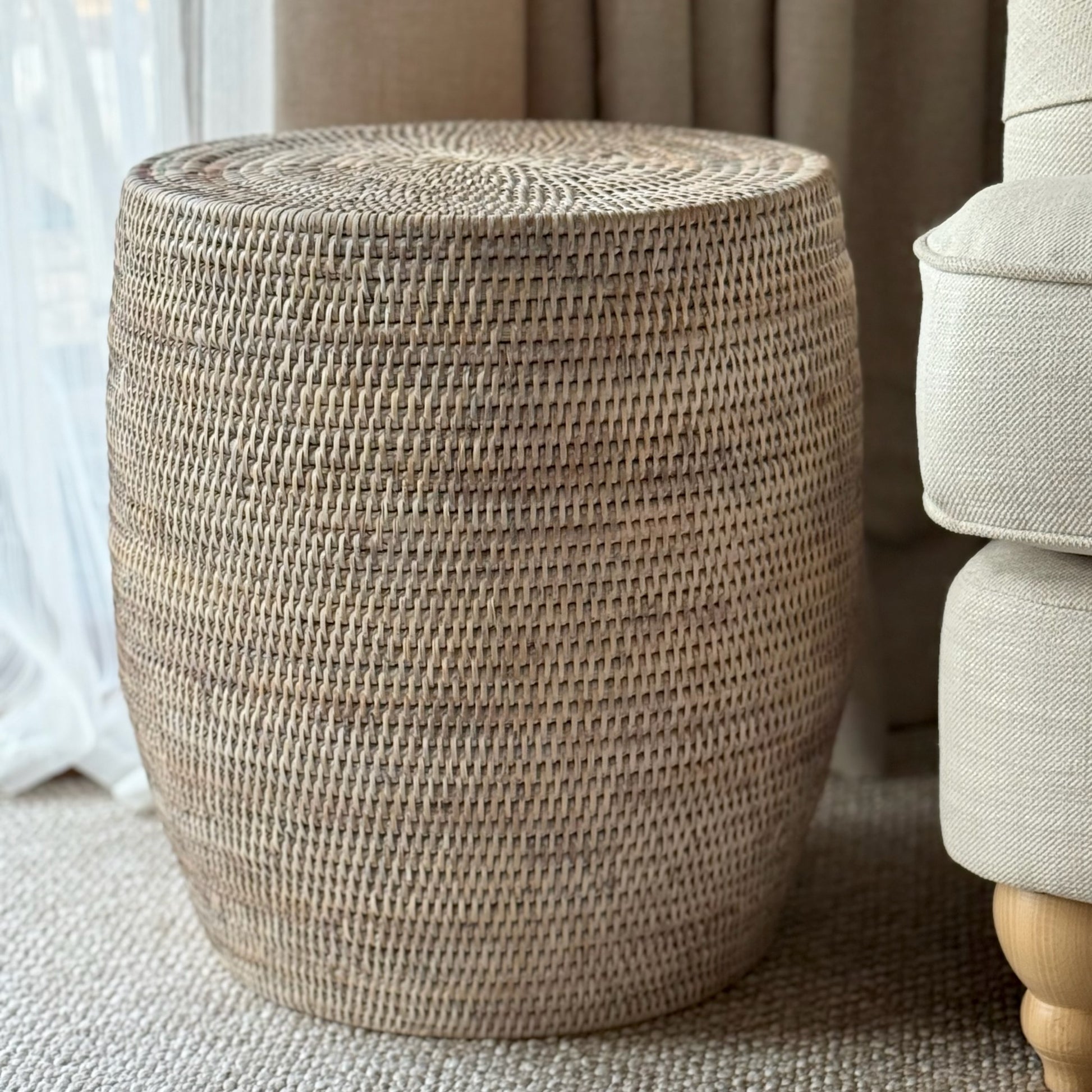 Woven stool in a home setting next to a sofa