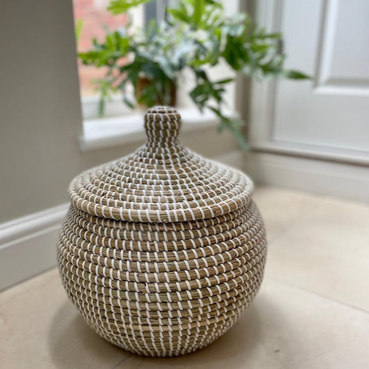 Handwoven natural seagrass basket styled on a neutral stone floor.
