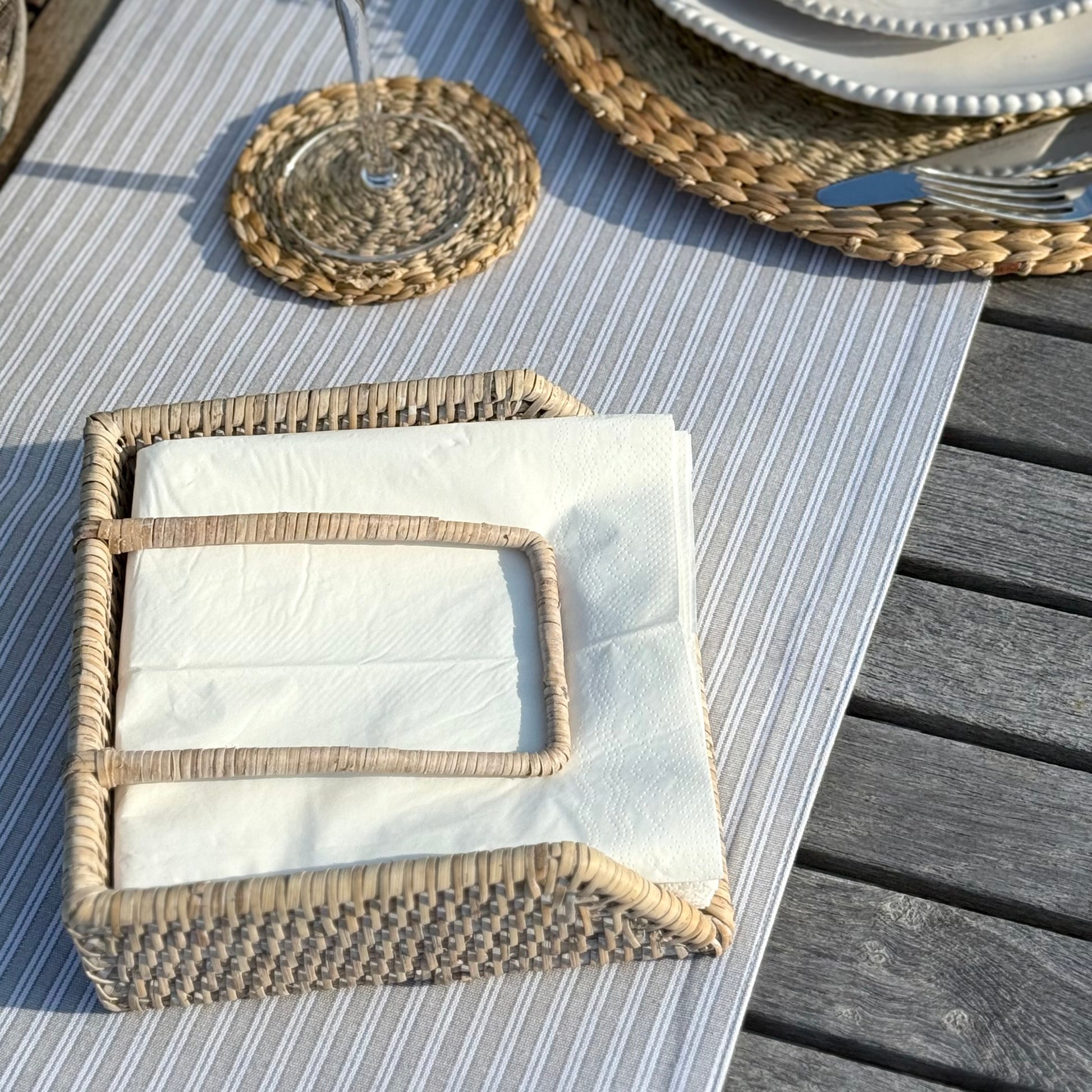Rustic rattan napkin holder crafted from natural materials with practical weighted arm.