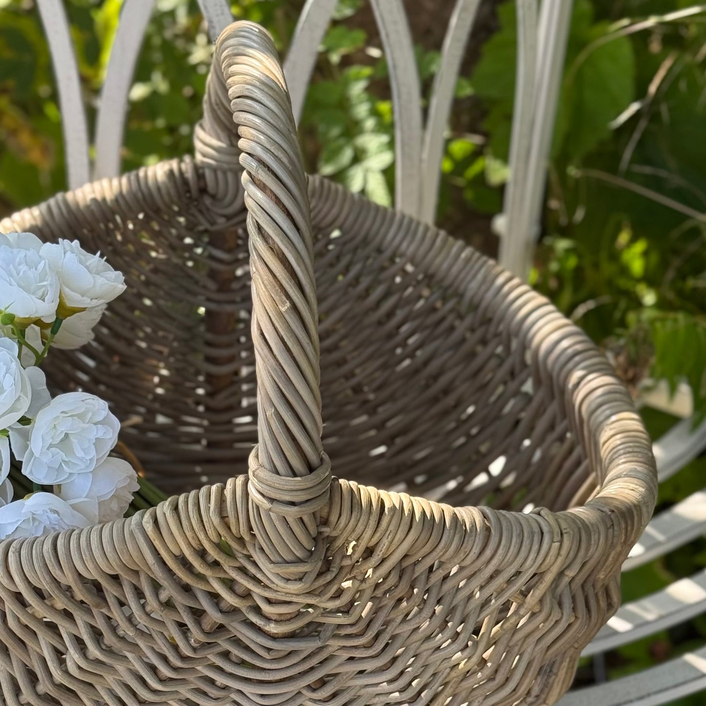 Handwoven rattan basket with circular handle, perfect for flowers, kindling or home storage.