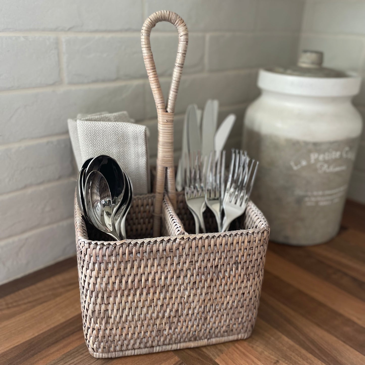 Rattan white washed table caddy styled on wooden kitchen worktop.