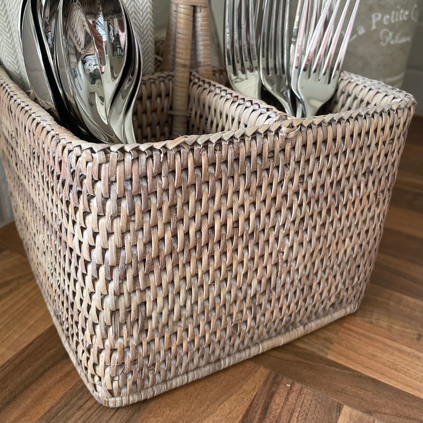 Close up of whitewashed rattan caddy texture. Shown filled with cutlery and napkins.