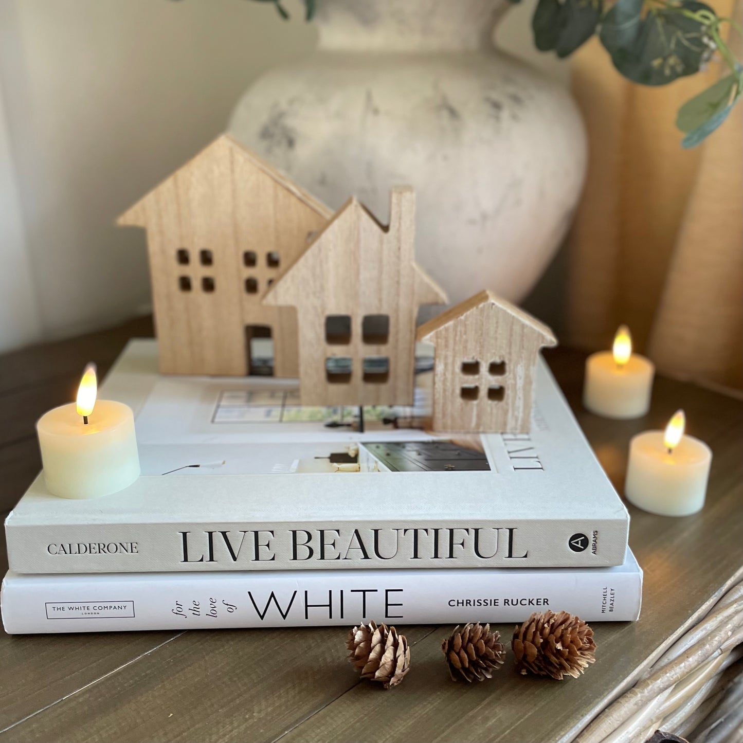 Cosy home table setting with real wax LED tea light candles. Styled on book and rattan storage box. 