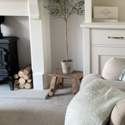 Reclaimed teak wooden display stool with rustic finish styled in a cosy home interior.