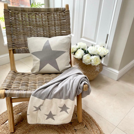 reversible star throw grey and cream, styled on a chair with a star detailed cushion.