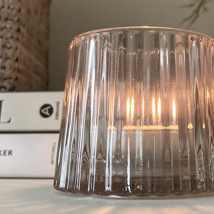 High quality glass tea light holder on shelf, styled with books and a plant.