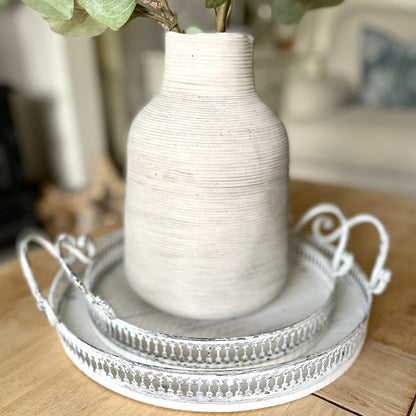 Rustic stone vase with irregular shape and textured earthy finish, styled on decorative trays.