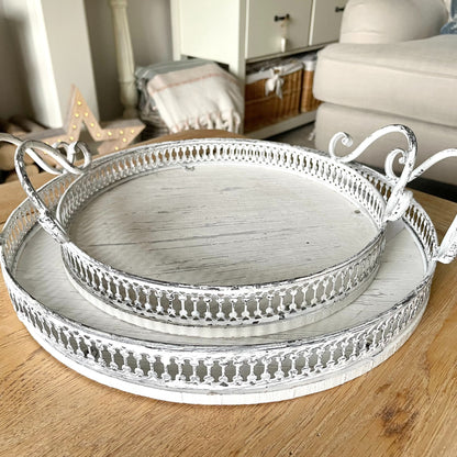 Round ornate white washed trays with handles, styled on a coffee table in a cosy living room.