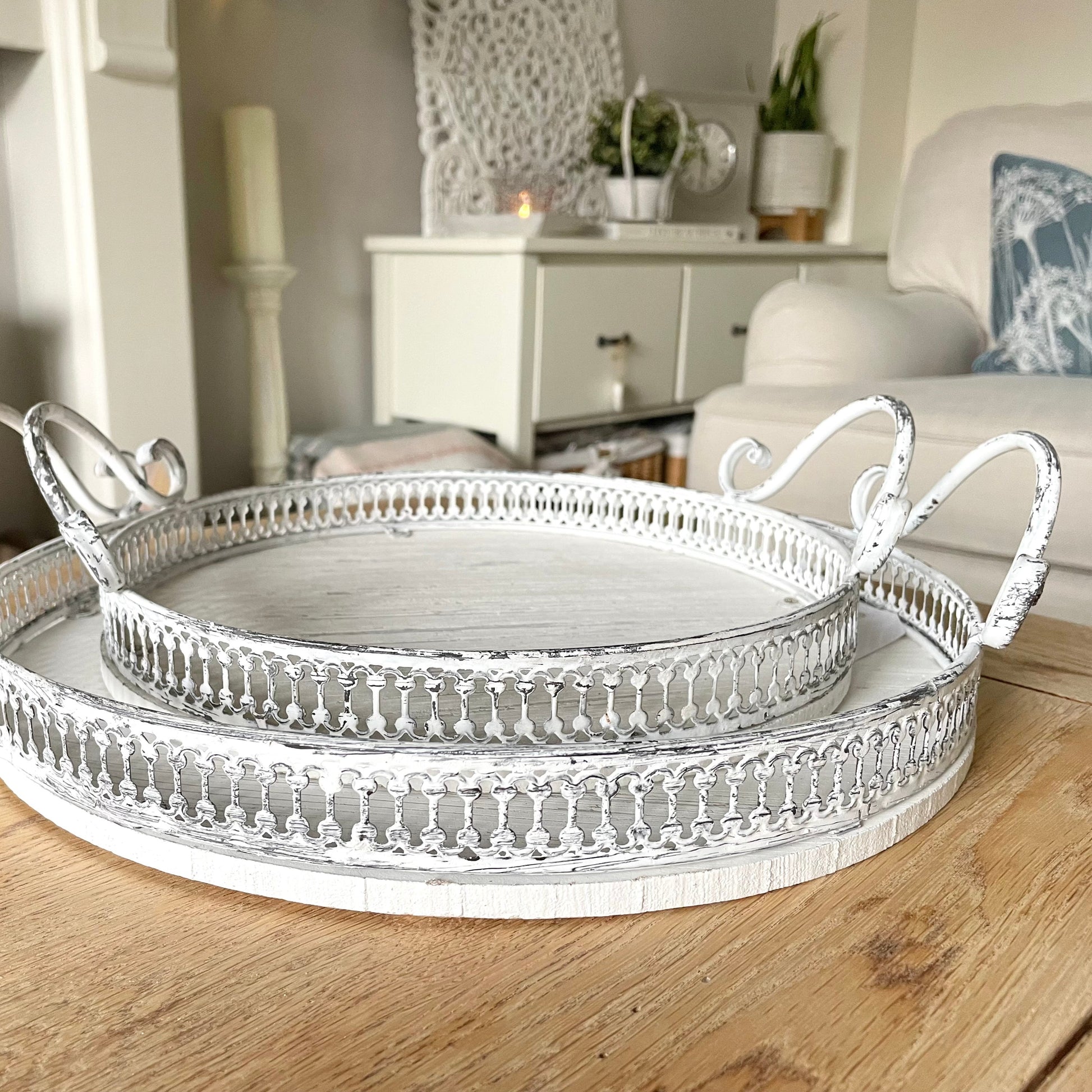 Round ornate white washed trays with handles, styled on a coffee table in a cosy living room.