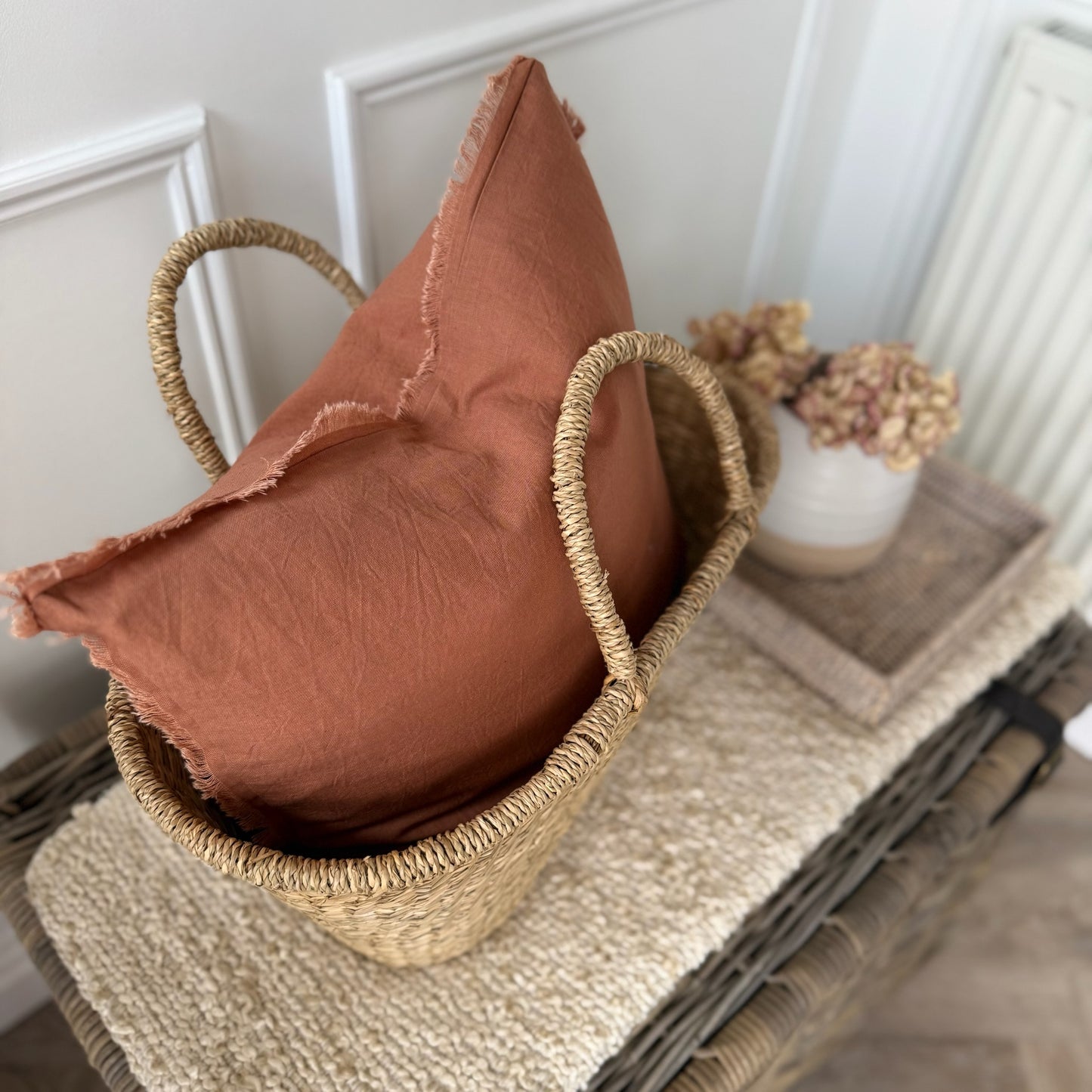 Decorative rust cotton cushion with frilled edges, styled on a sofa for a cosy, textured feel.