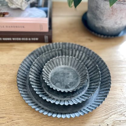 Rustic fluted zinc plate styled with a candle on a neutral table.