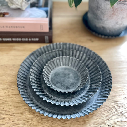Rustic fluted zinc plate styled with a candle on a neutral table.