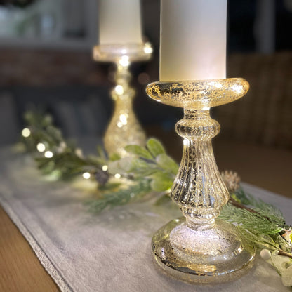 glass effect LED candlestick holder - 24 cm height styled on a table with garland and table runner. Battery operated.