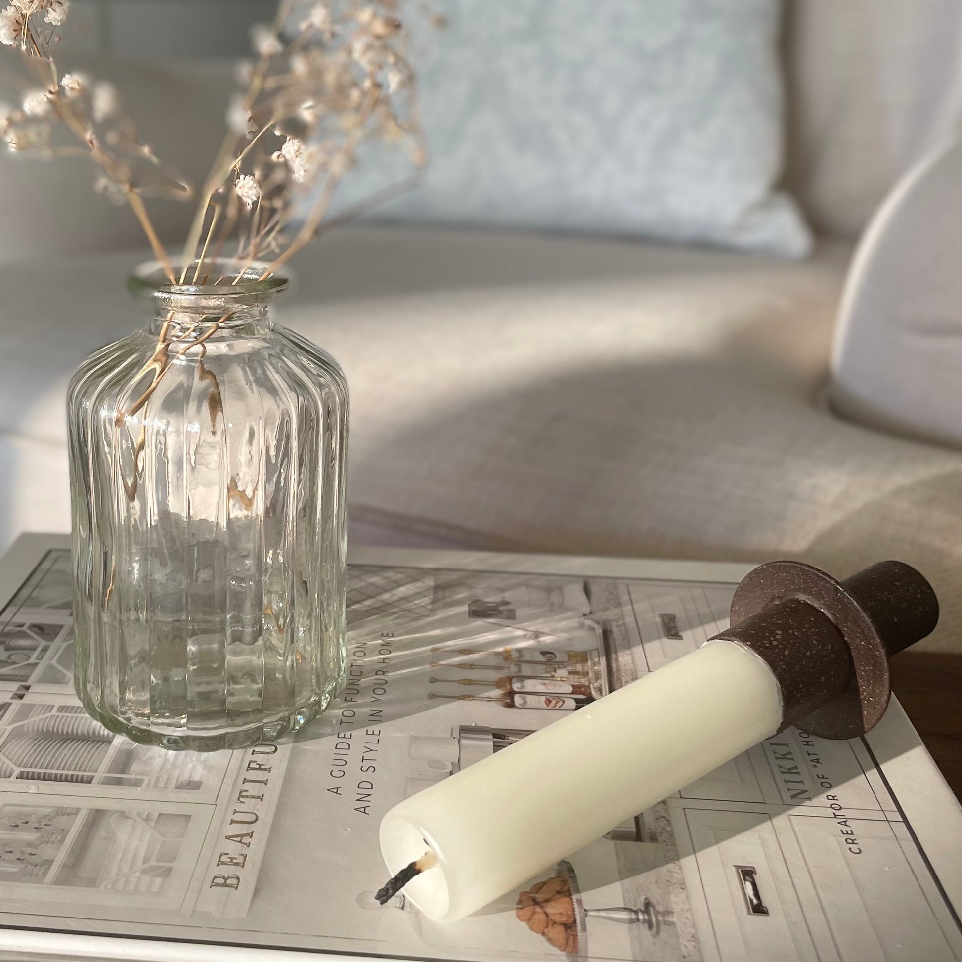 Close up of bottle top candle holder on a bud vase. Styled on a book with a short candle.