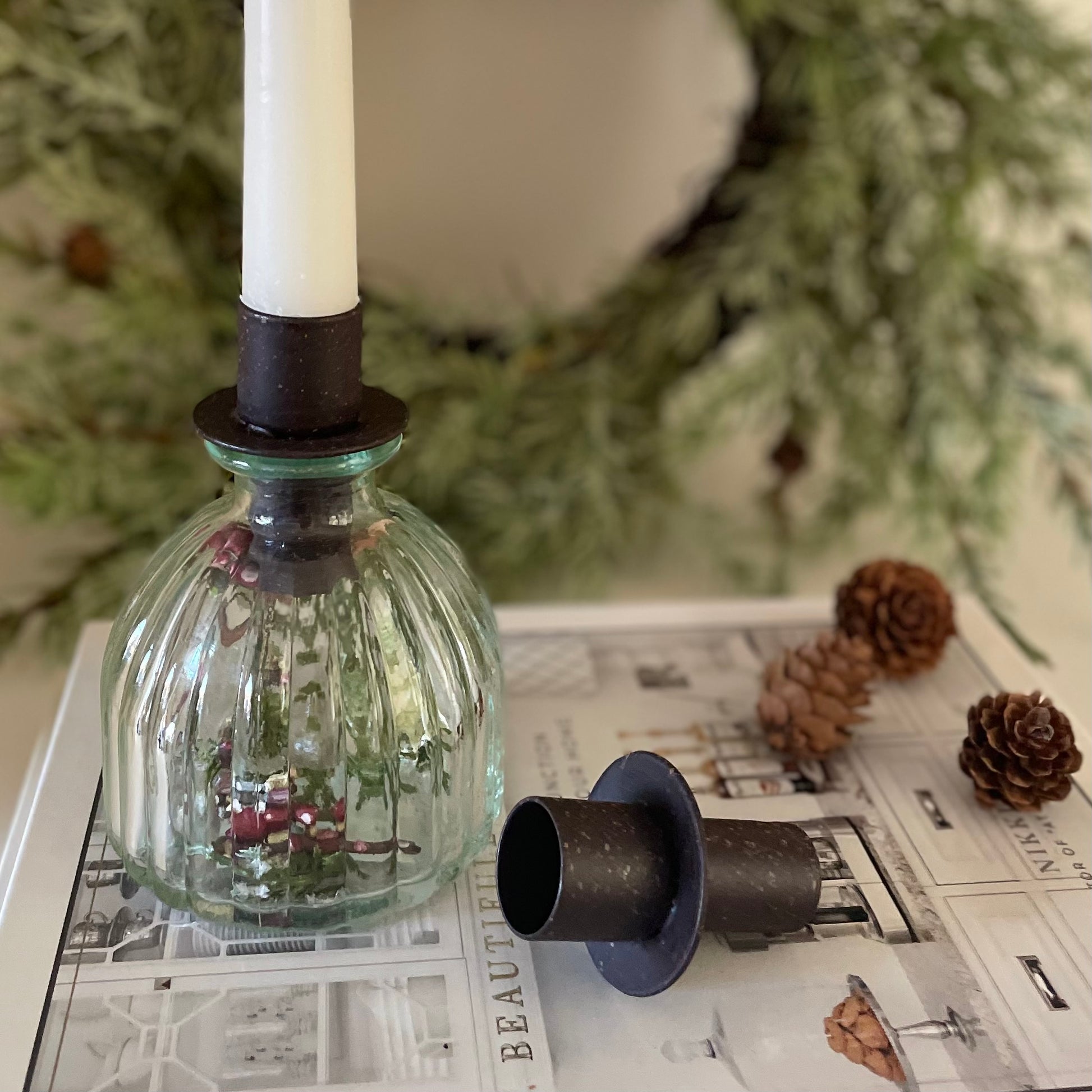Metal candle holder creating cosy ambient light on a white shelf with decorations.
