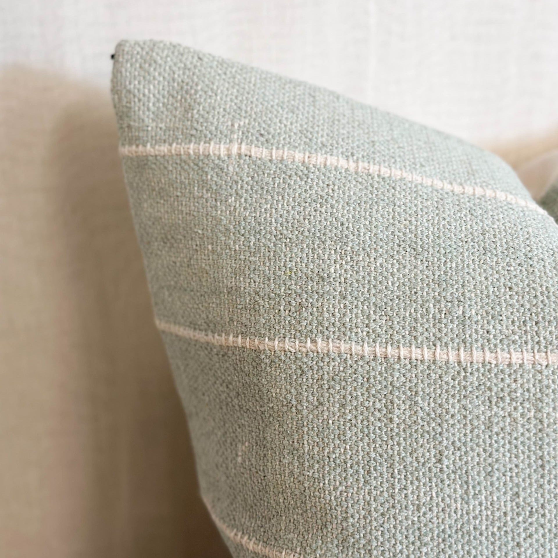 Soft cotton sage green cushion with subtle stripes, perfect for layering on sofas, chairs or beds.