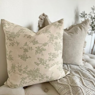 Country style sage green floral cushion with subtle pattern and neutral tones, perfect for layering with throws.