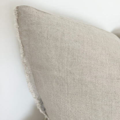 Close up of linen sand coloured cushion with frayed edges.